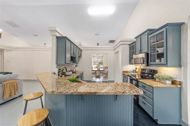 kitchen featuring a peninsula, visible vents, stainless steel microwave, and a kitchen breakfast bar