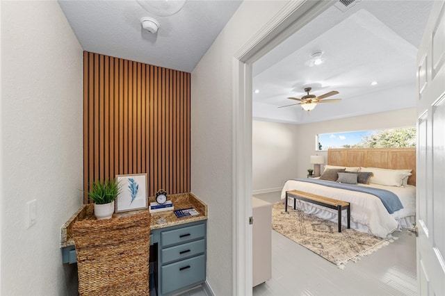 bedroom featuring visible vents, a textured wall, a ceiling fan, a textured ceiling, and baseboards