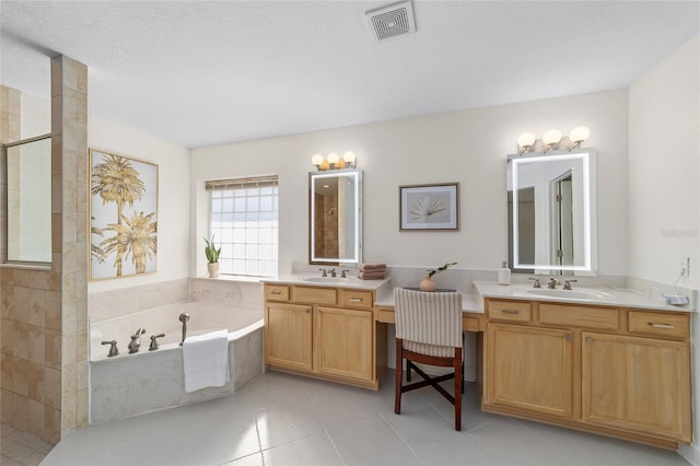 bathroom with a garden tub, two vanities, a sink, and visible vents