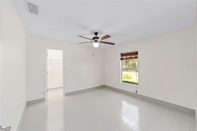 spare room with a ceiling fan, visible vents, and baseboards