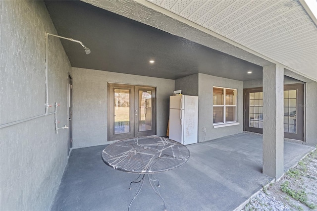 entrance to property with a patio area, stucco siding, and french doors