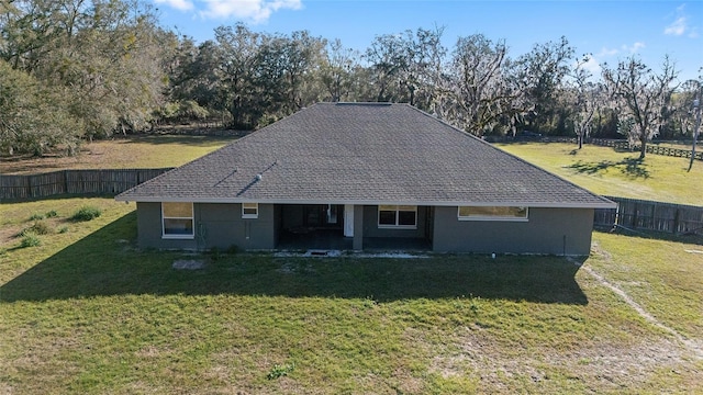 view of front of house with a fenced backyard, a front lawn, and roof with shingles