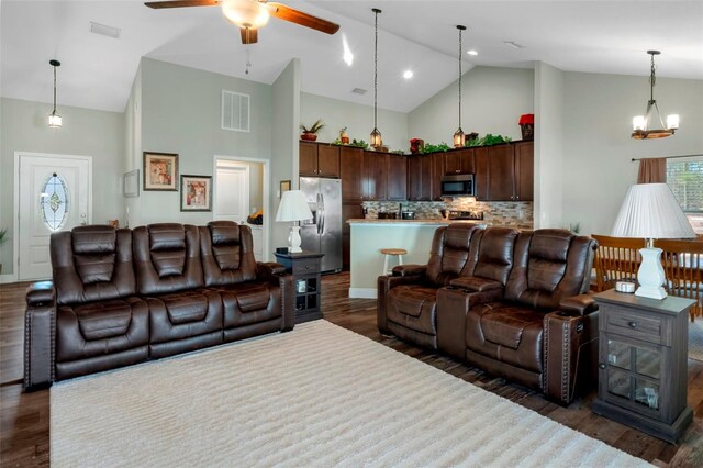 living area with high vaulted ceiling, visible vents, dark wood finished floors, and ceiling fan with notable chandelier