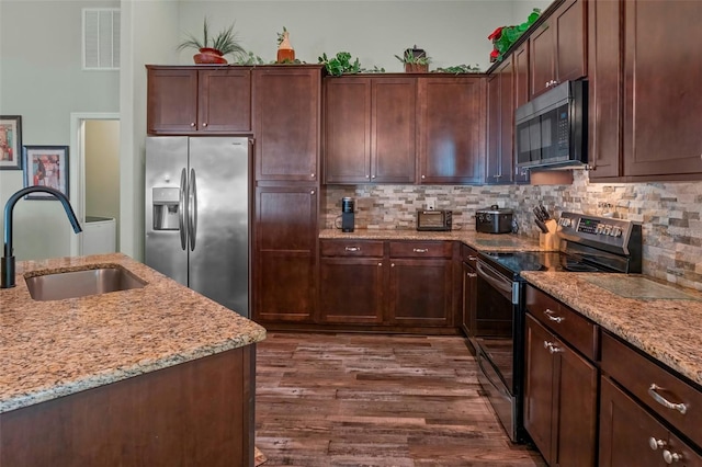 kitchen featuring visible vents, dark wood finished floors, appliances with stainless steel finishes, light stone countertops, and a sink