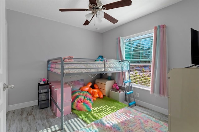 bedroom with light wood finished floors, a ceiling fan, and baseboards