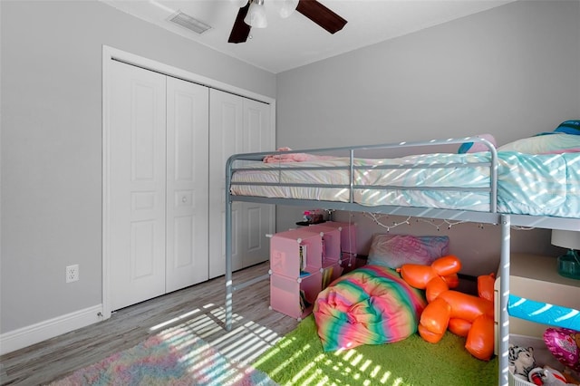 bedroom featuring baseboards, visible vents, ceiling fan, wood finished floors, and a closet