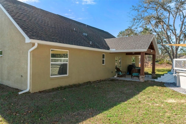 back of property featuring a patio area, roof with shingles, a yard, and stucco siding