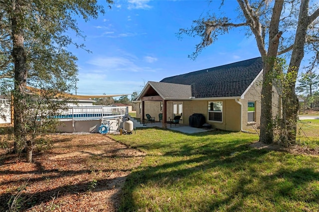 back of house with an outdoor pool, roof with shingles, a yard, a patio area, and stucco siding