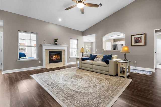 living room featuring dark wood-style floors, visible vents, baseboards, high vaulted ceiling, and a tile fireplace