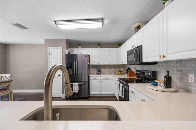 kitchen featuring a sink, visible vents, black appliances, and white cabinetry