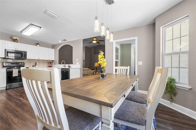 dining room featuring visible vents, a ceiling fan, dark wood-style floors, arched walkways, and baseboards