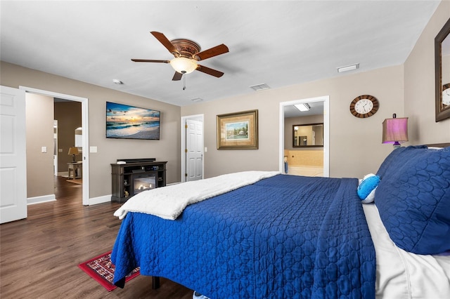 bedroom with dark wood finished floors, a ceiling fan, ensuite bath, and baseboards