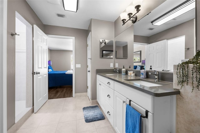 ensuite bathroom featuring tile patterned flooring, visible vents, ensuite bath, and a sink