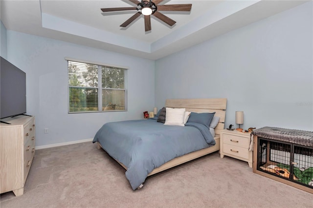 carpeted bedroom featuring a raised ceiling and ceiling fan