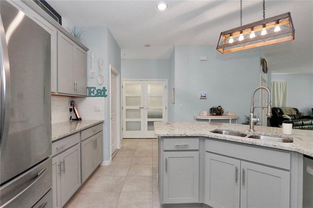 kitchen featuring sink, gray cabinetry, stainless steel fridge, and decorative light fixtures