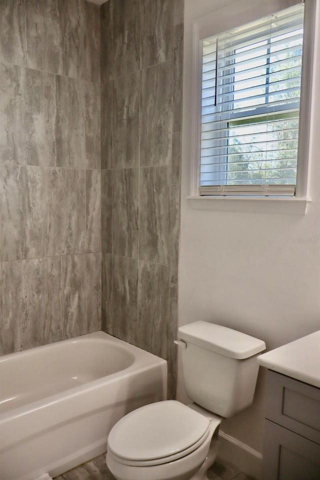 full bathroom featuring tiled shower / bath, vanity, and toilet