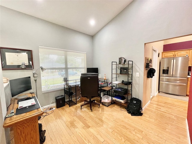 office area with high vaulted ceiling and light hardwood / wood-style floors