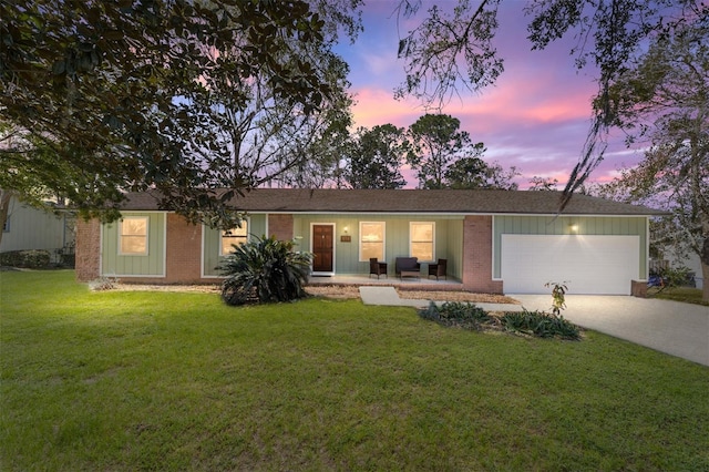 ranch-style house featuring a garage, concrete driveway, brick siding, and a front lawn