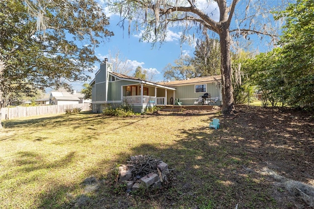 back of house with a chimney, fence, and a yard