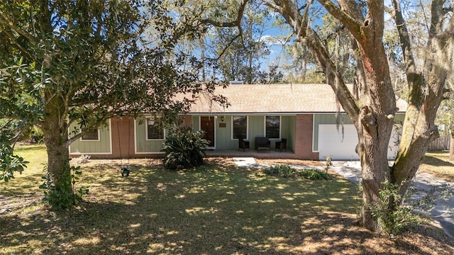 ranch-style home featuring a garage, covered porch, brick siding, and a front lawn