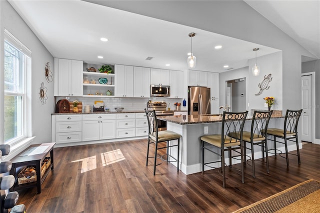 kitchen with stainless steel appliances, white cabinetry, dark stone countertops, and open shelves