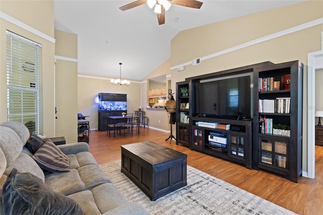 living room with ceiling fan with notable chandelier, wood finished floors, visible vents, baseboards, and vaulted ceiling