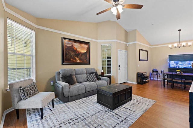 living room featuring lofted ceiling, light wood-style flooring, baseboards, and ceiling fan with notable chandelier