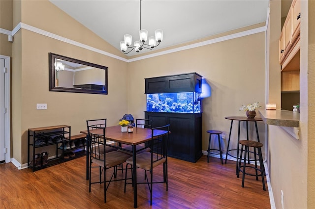 dining room featuring ornamental molding, lofted ceiling, an inviting chandelier, and wood finished floors