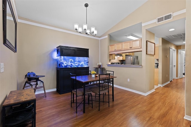 dining space featuring an inviting chandelier, visible vents, vaulted ceiling, and wood finished floors