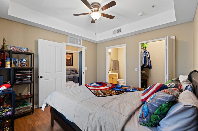 bedroom with visible vents, a tray ceiling, and wood finished floors