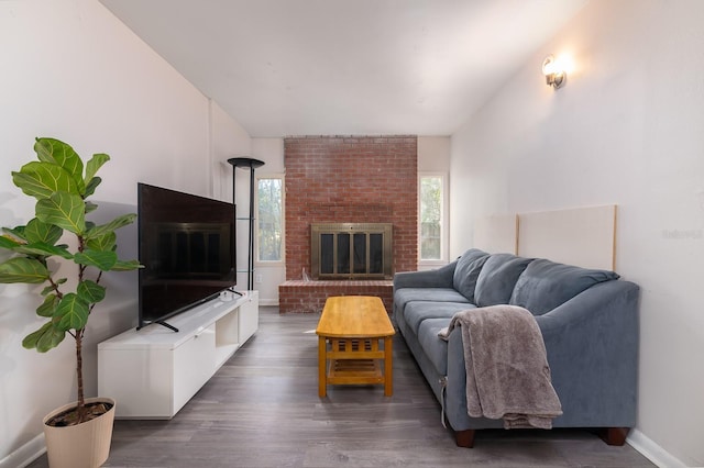 living room with a healthy amount of sunlight, dark wood-style floors, a brick fireplace, and baseboards