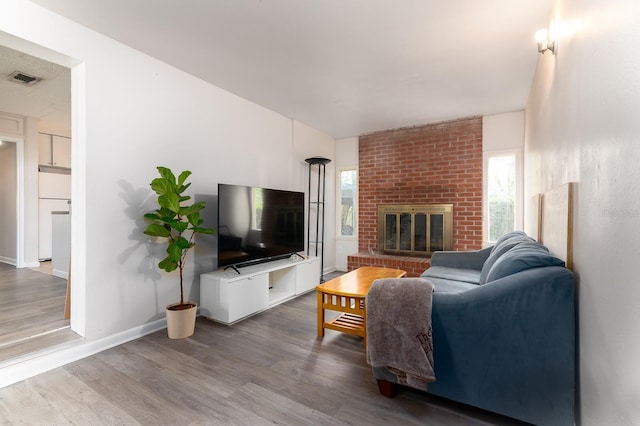 living room featuring a wealth of natural light, visible vents, a fireplace, and wood finished floors