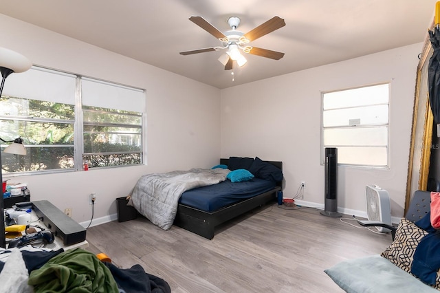 bedroom with light wood-type flooring, ceiling fan, and baseboards