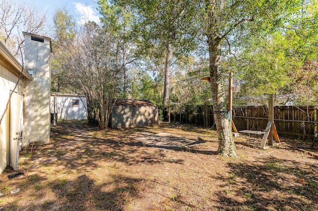 view of yard with a storage shed, a fenced backyard, and an outdoor structure