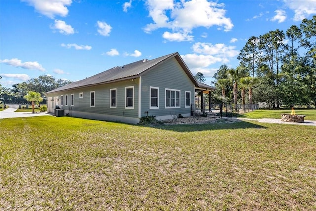 view of property exterior featuring metal roof, a yard, an outdoor fire pit, and central AC unit