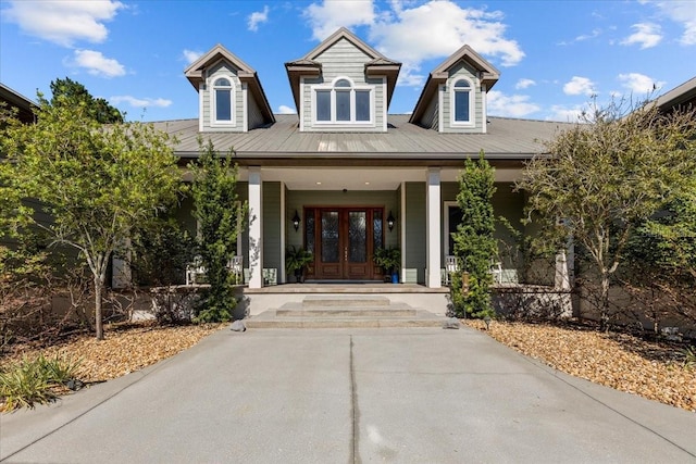 view of exterior entry with covered porch, metal roof, and french doors