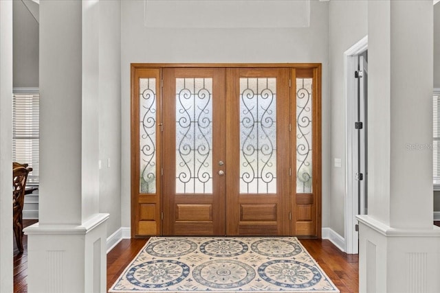 entrance foyer with baseboards, dark wood finished floors, and ornate columns