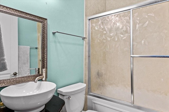 full bath featuring shower / bath combination with glass door, a sink, and toilet