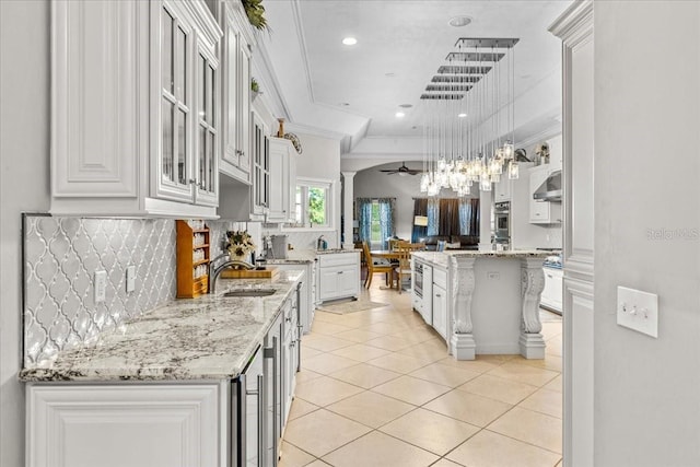 kitchen with a center island, hanging light fixtures, glass insert cabinets, white cabinets, and a sink