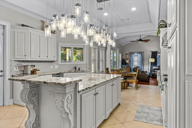 kitchen with pendant lighting, light tile patterned floors, decorative backsplash, open floor plan, and white cabinetry