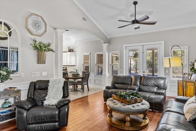 living area with lofted ceiling, wainscoting, visible vents, and decorative columns