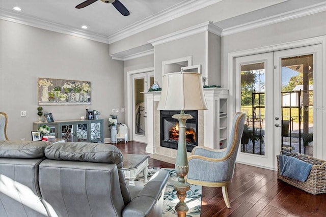 living area with dark wood-style flooring, french doors, crown molding, recessed lighting, and a tiled fireplace