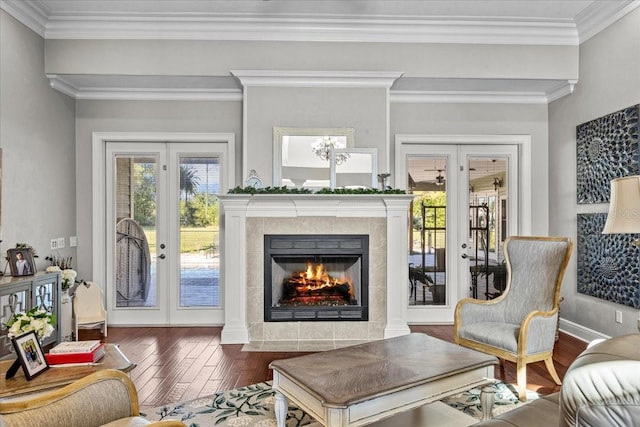 living area featuring a tile fireplace, dark wood finished floors, crown molding, and french doors