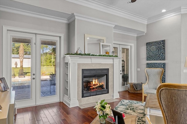 living area featuring french doors, dark wood-style flooring, a fireplace, and crown molding