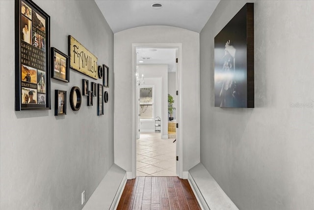 hallway with lofted ceiling, baseboards, and wood finished floors