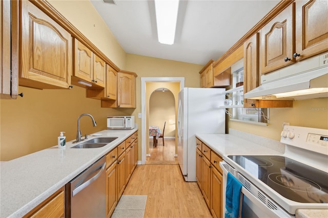 kitchen with lofted ceiling, sink, white appliances, and light wood-type flooring