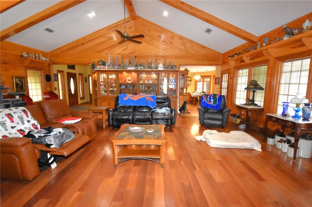 living room featuring high vaulted ceiling, wooden walls, ceiling fan, beam ceiling, and hardwood / wood-style floors