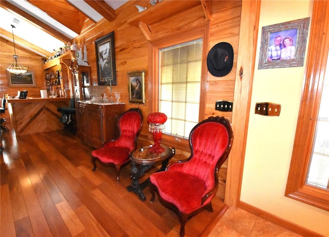 living area with light wood-type flooring, lofted ceiling with beams, and wood walls