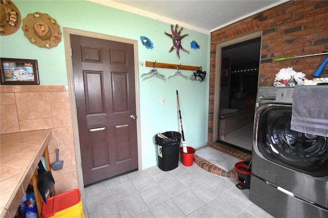 washroom with light tile patterned flooring, washer / dryer, and tile walls