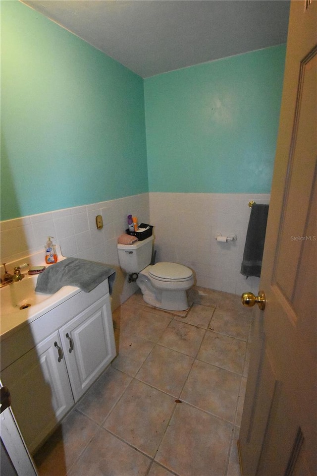 bathroom featuring tile patterned flooring, vanity, tile walls, and toilet